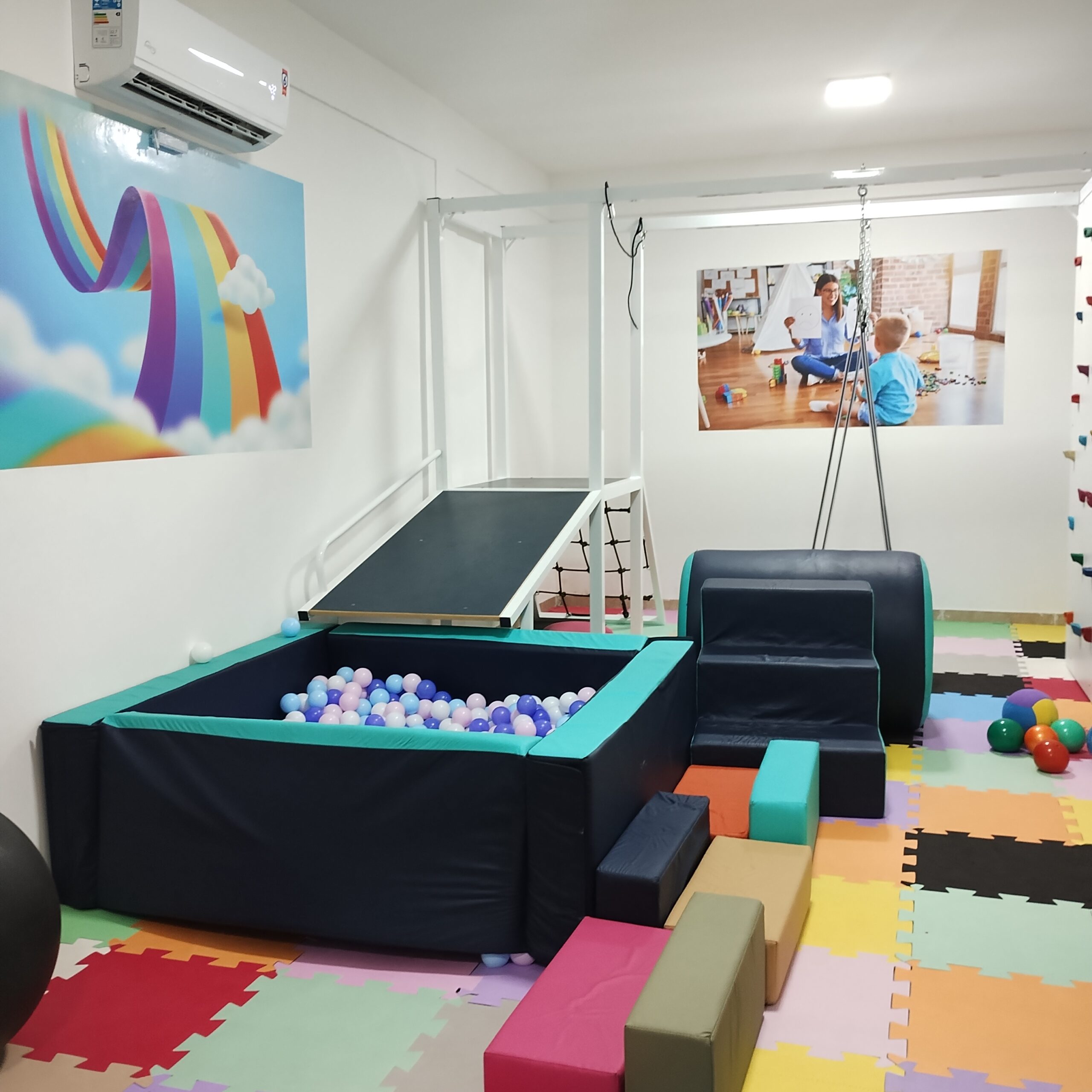 Espaço terapêutico da clínica com equipamentos e piso colorido